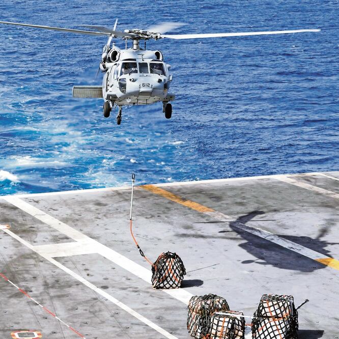 Un helicóptero traslada carga del buque USNS Arctic al portaaviones Abraham Lincon, que está en el Mar Arábigo. REUTERS