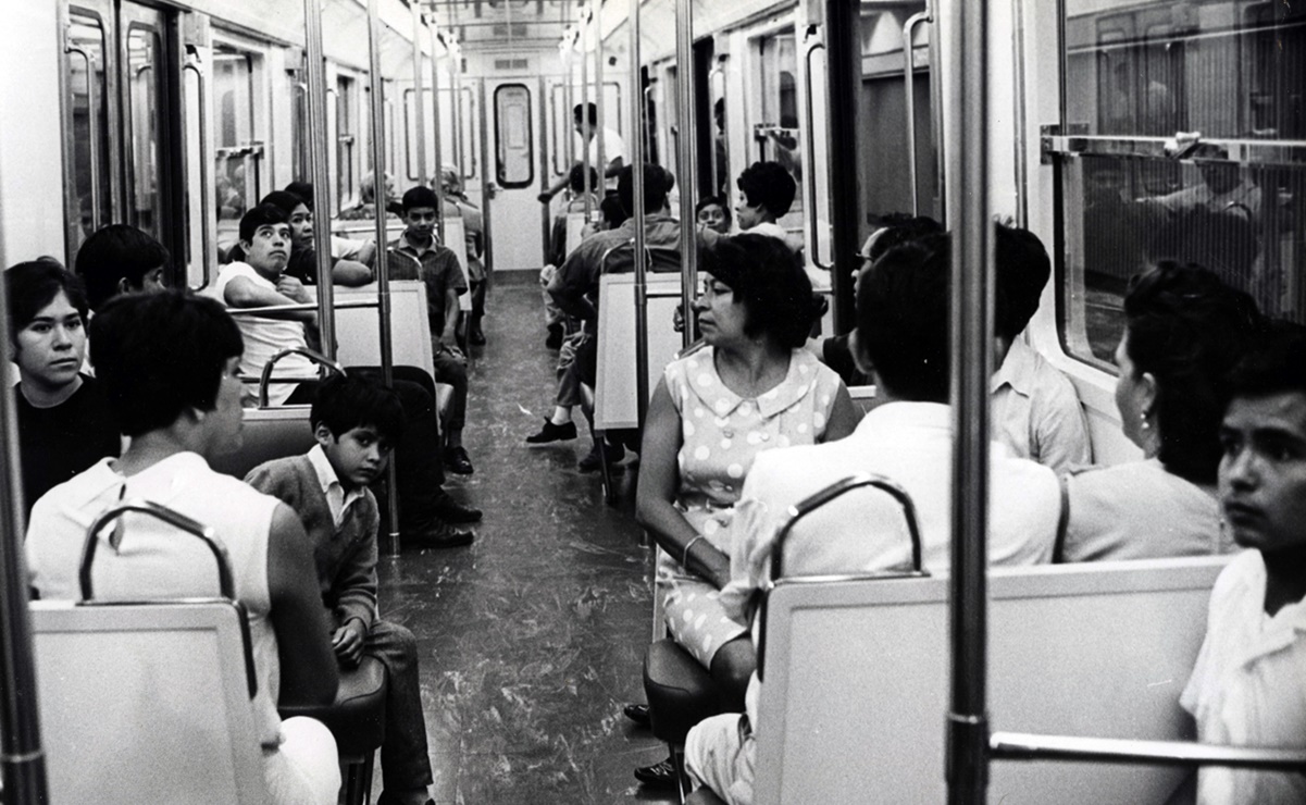  Vagón interior del metro,  imagen a blanco y negro donde se encuentran varias personas sentadas entre ellas mujeres niños y hombres jóvenes
    
