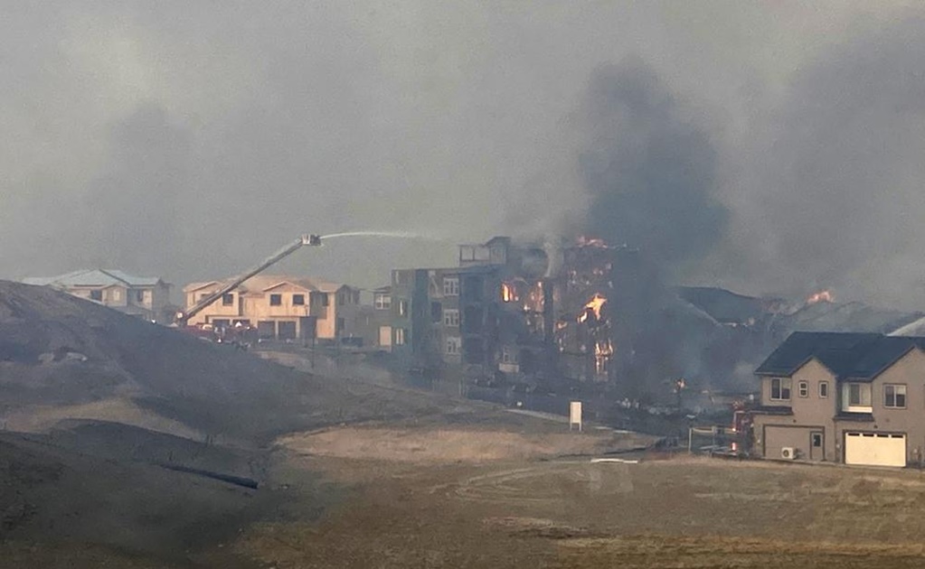 Los bomberos rocían agua en una estructura mientras crece un incendio forestal, el jueves 30 de diciembre de 2021, en Superior, Colorado.